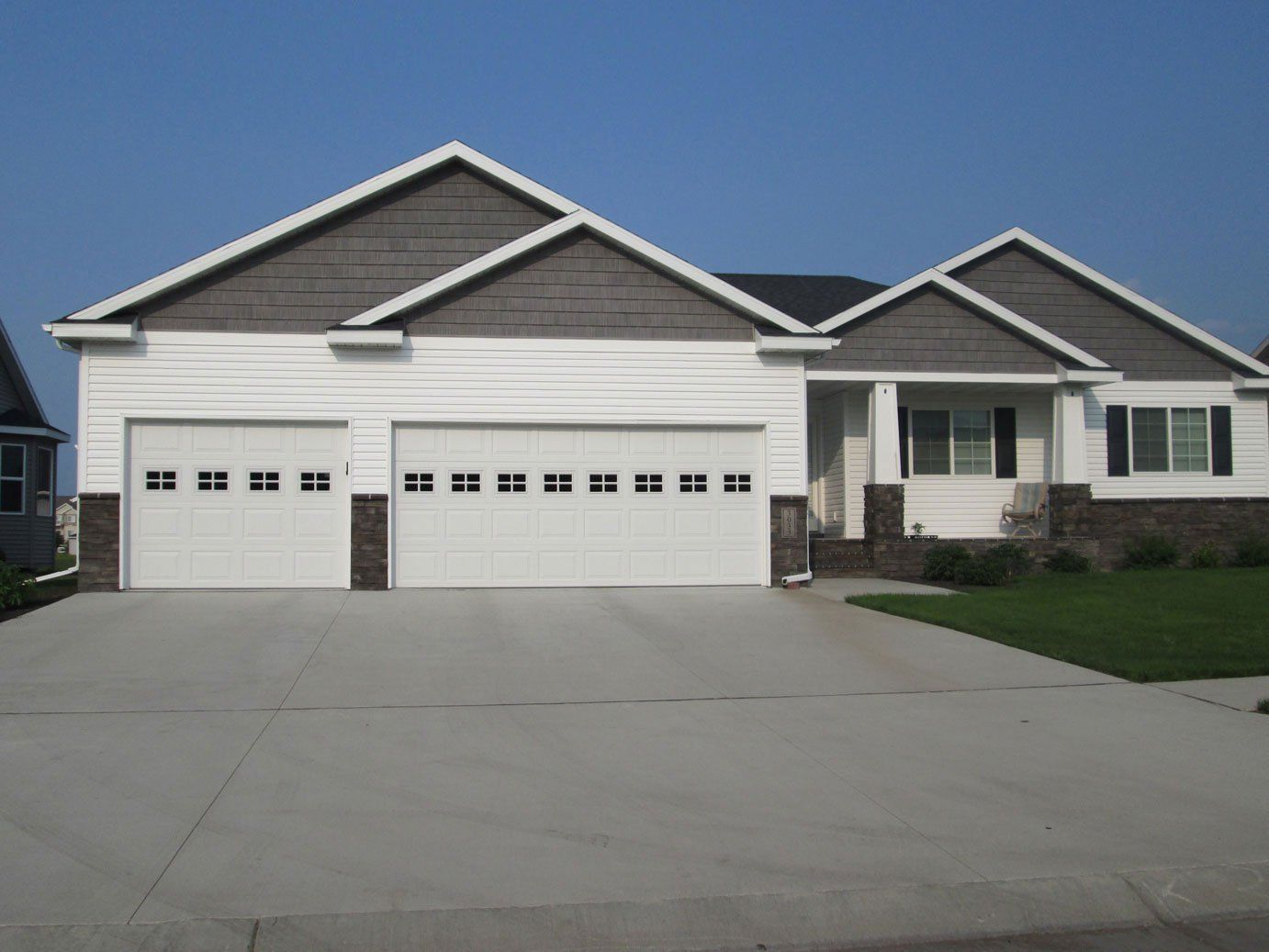 Suburban single-story house with white garage doors and a wide concrete driveway