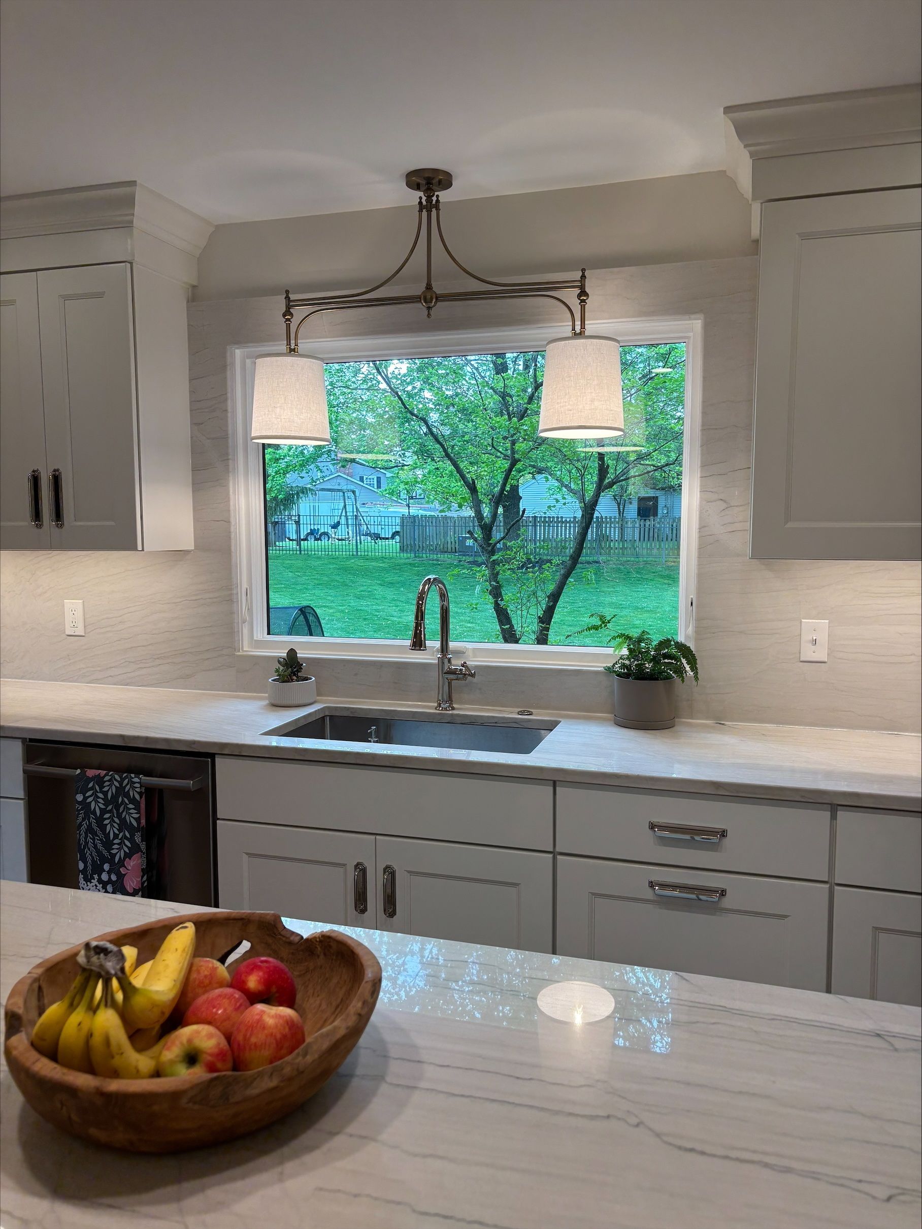 A kitchen with a sink and a bowl of fruit on the counter