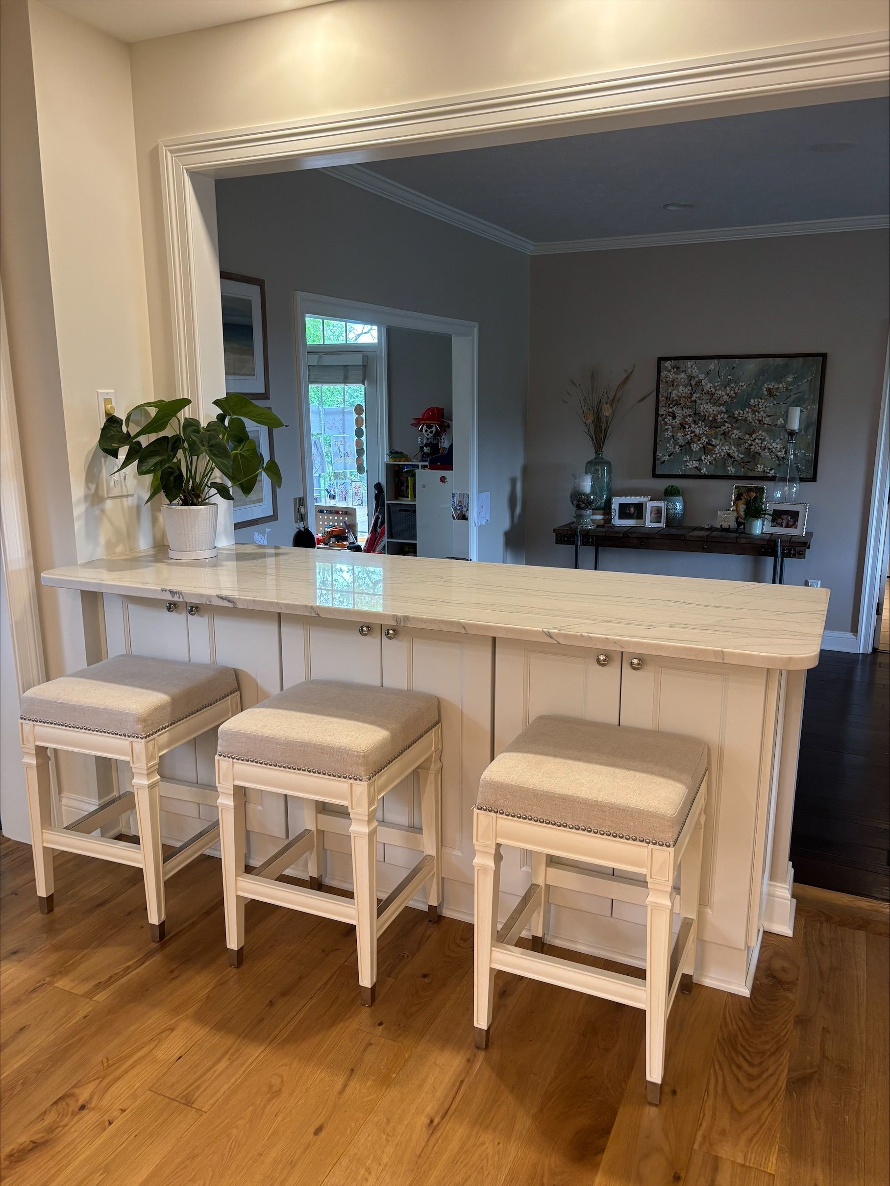 A kitchen with a bar and stools and a marble counter top.