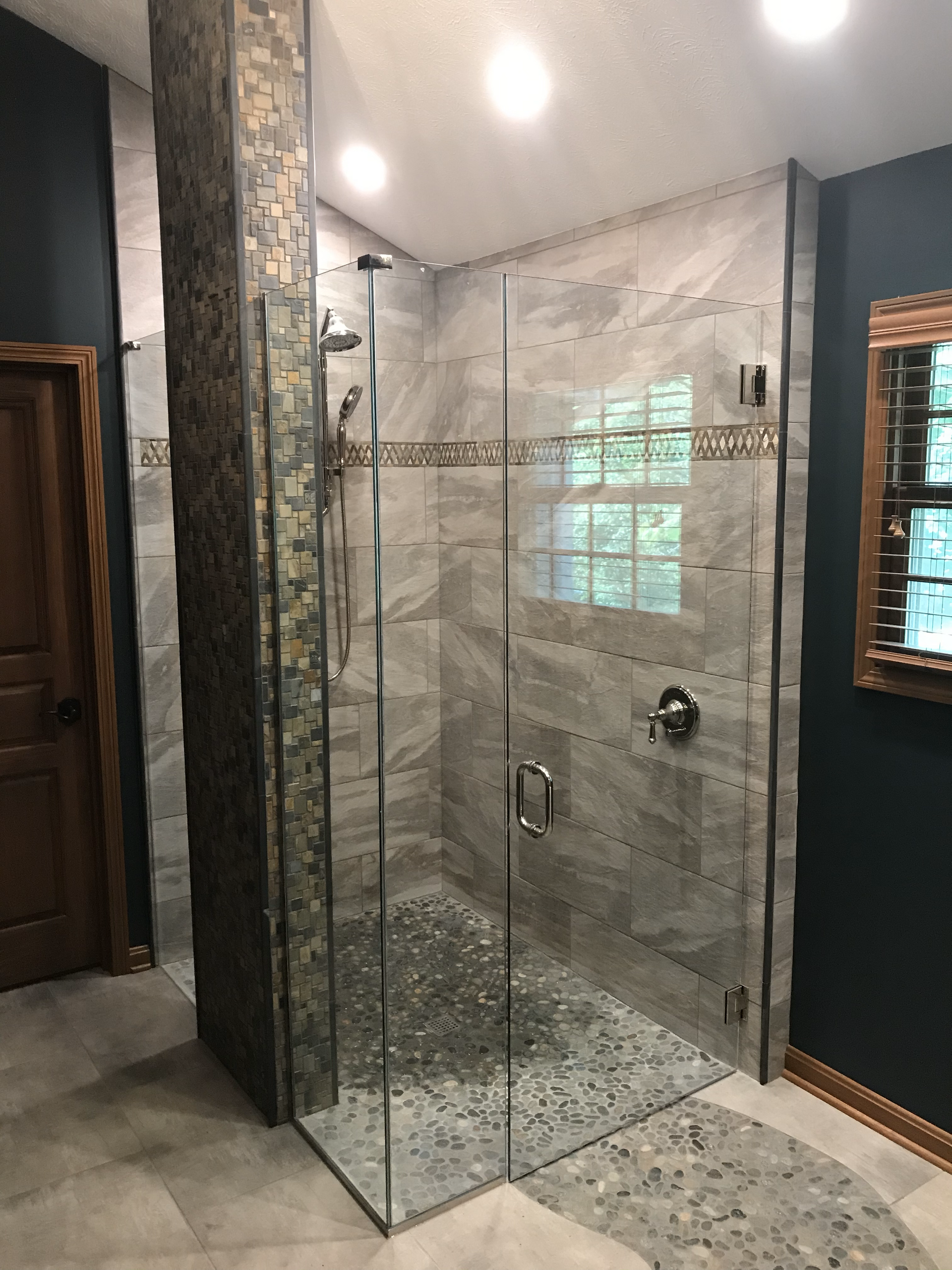 A bathroom with a walk in shower and a mirror.