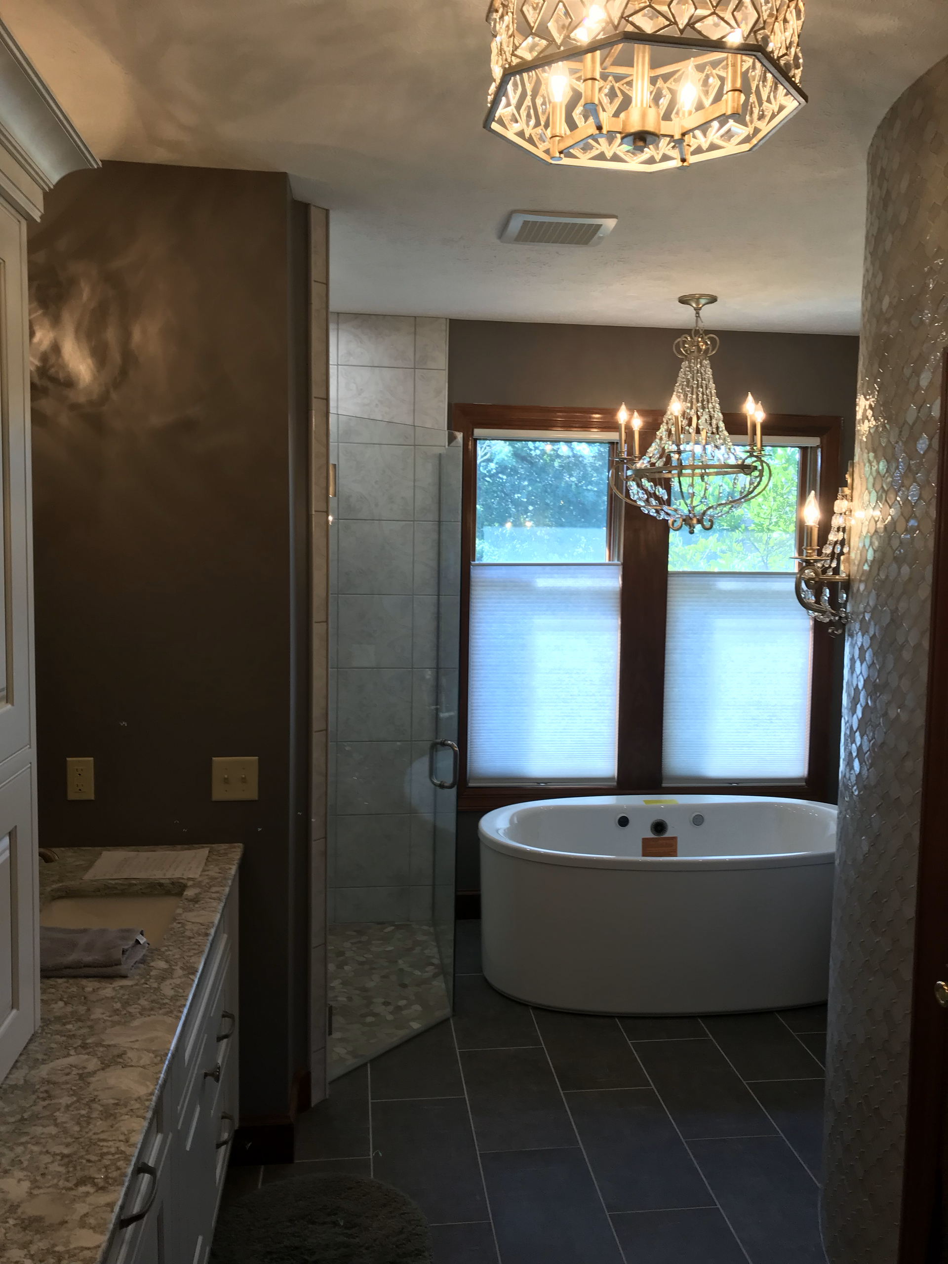 A bathroom with a tub and a chandelier hanging from the ceiling