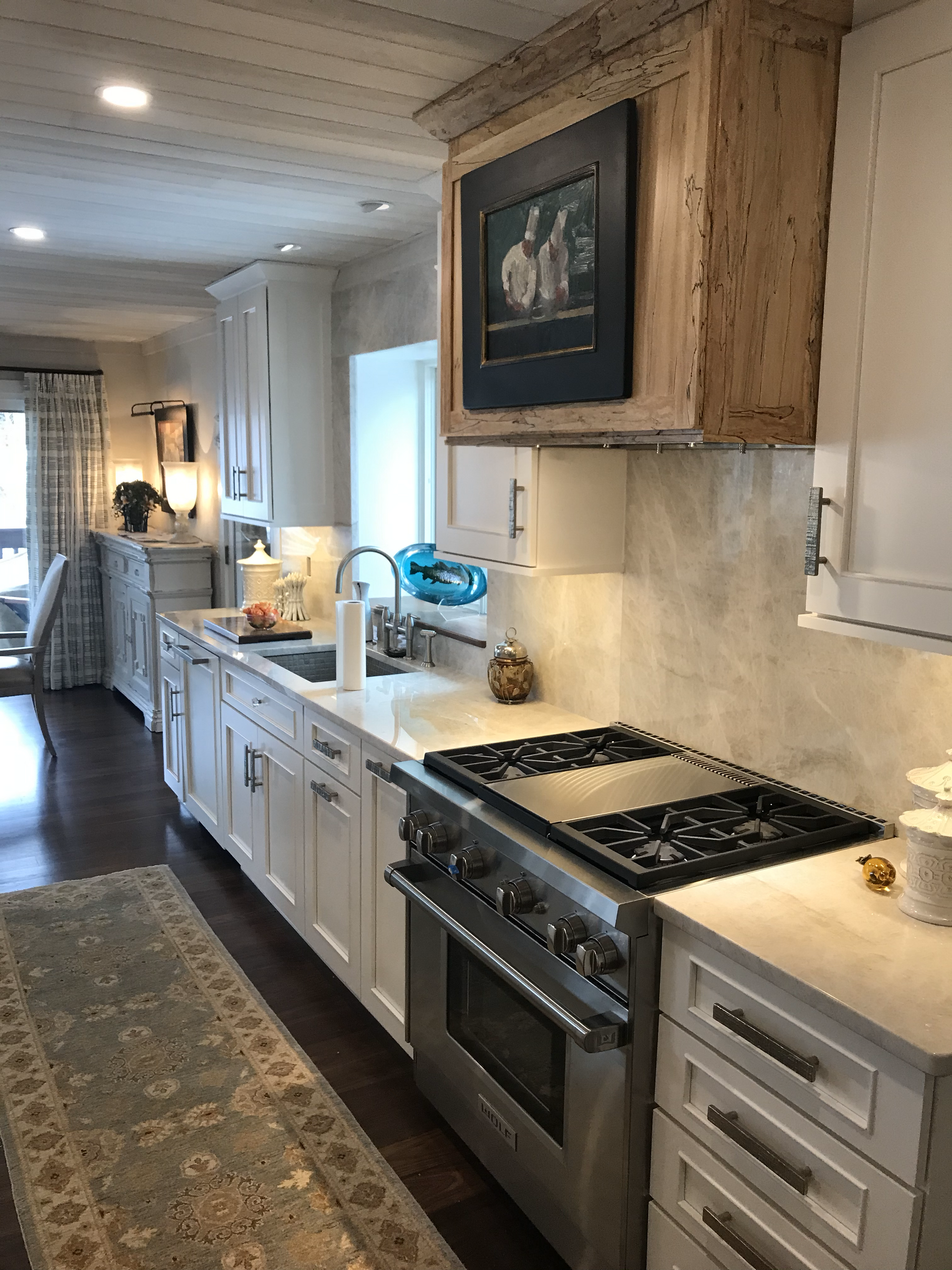 A kitchen with white cabinets , stainless steel appliances , a stove and a sink.