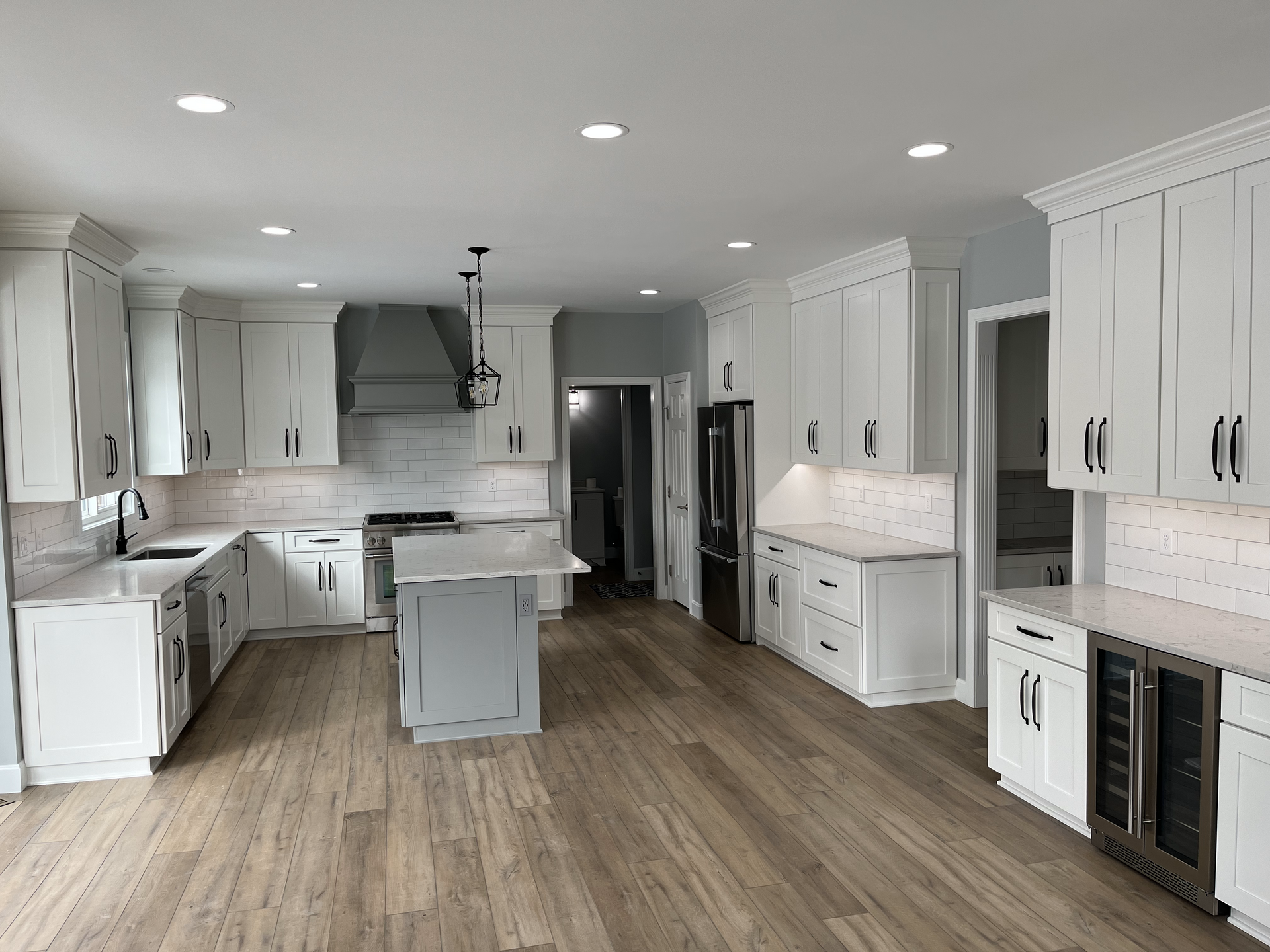 A large kitchen with white cabinets and hardwood floors.