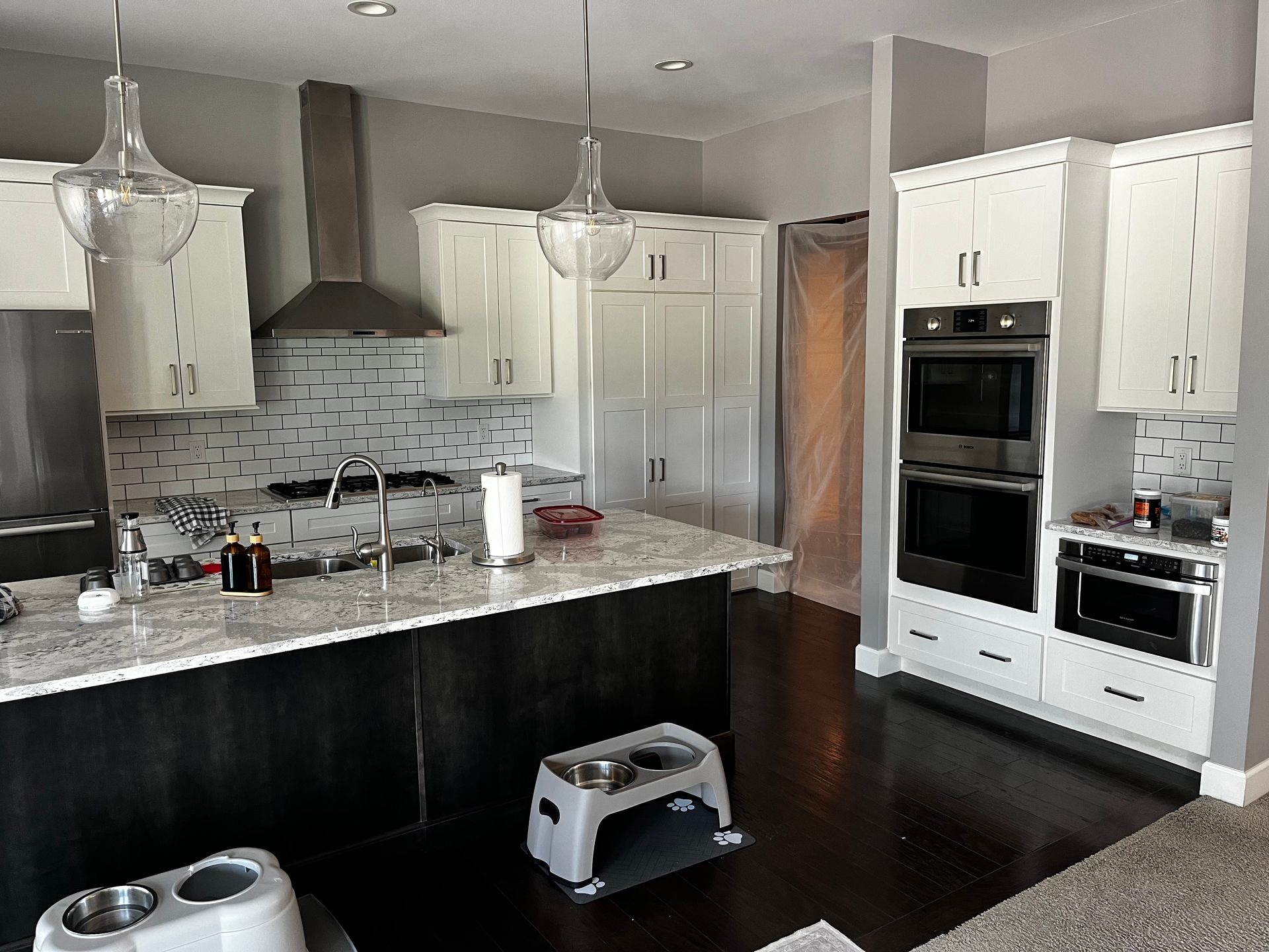 Modern kitchen with dark cabinets, white appliances, granite island, and pendant lights