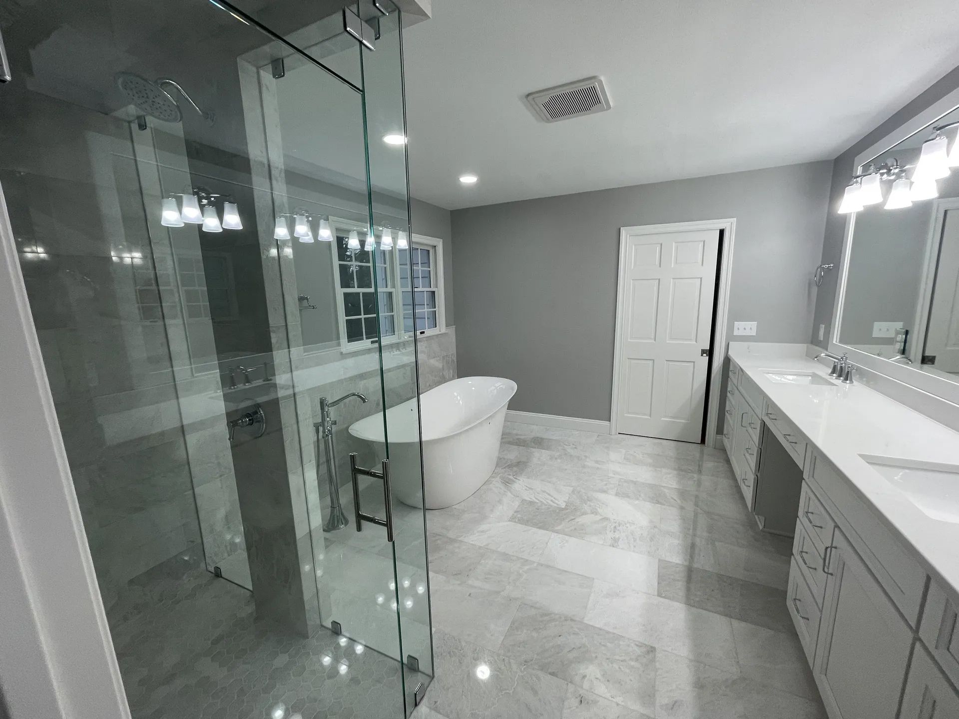 A bathroom with a tub, sinks, and a walk in shower.