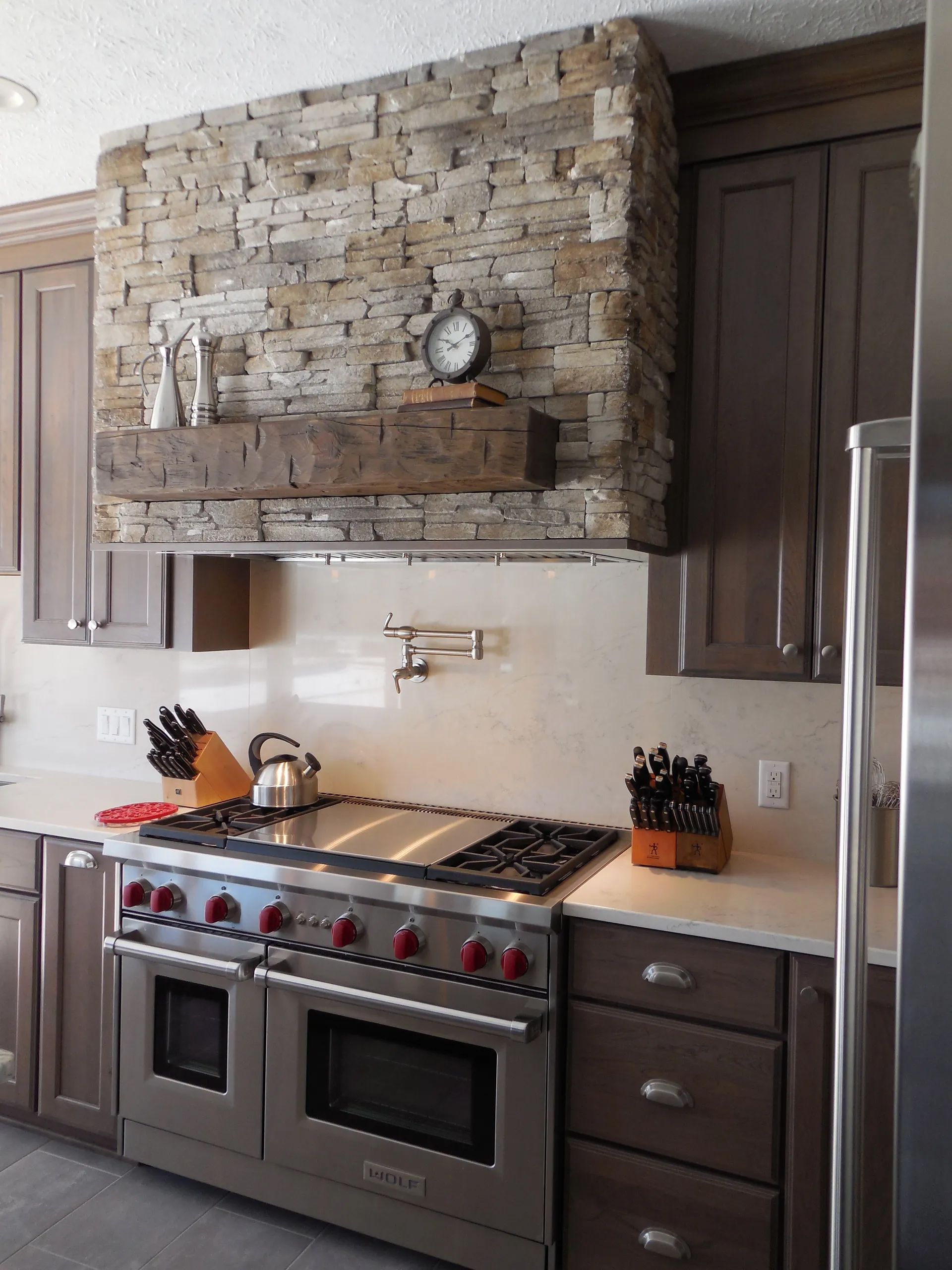 A kitchen with stainless steel appliances and a stone wall