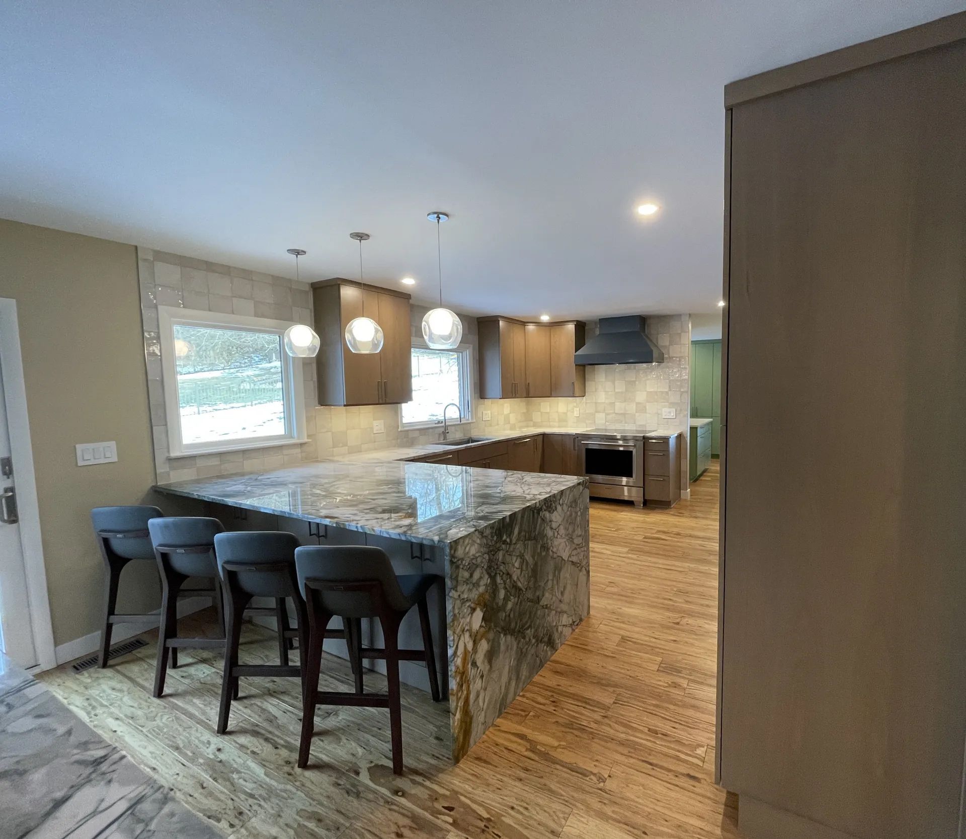 A kitchen with a marble counter top and stools