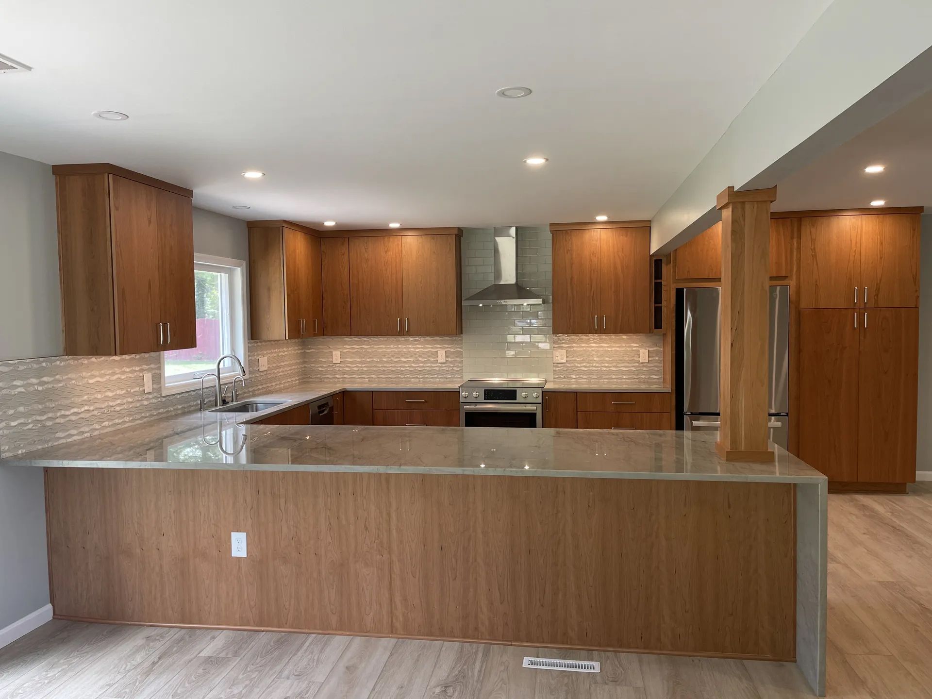 A kitchen with wooden cabinets, granite counter tops, stainless steel appliances and a large island.