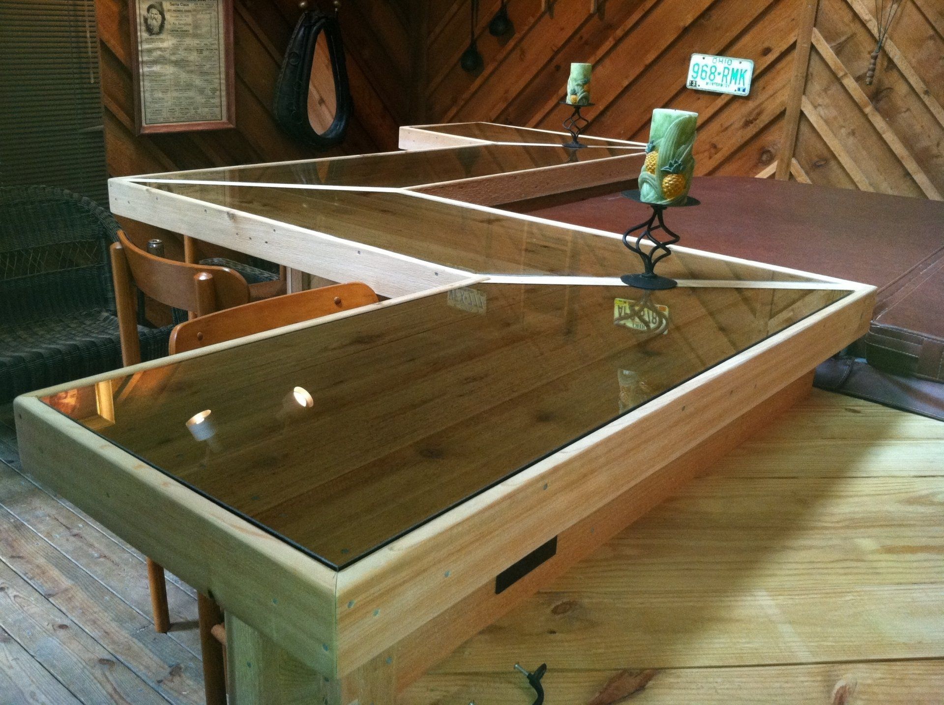 A wooden table with a glass top and two candles on it