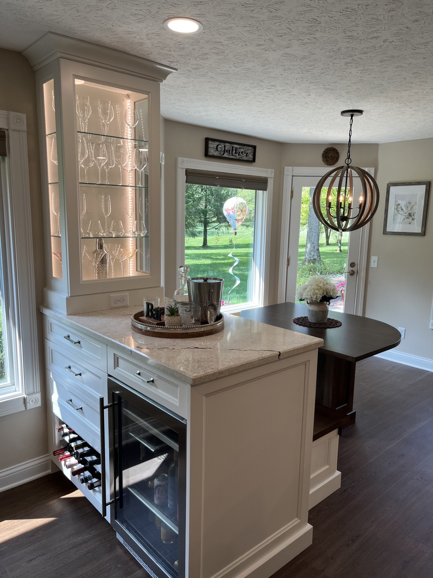 A kitchen with a wine cooler and a dining table.