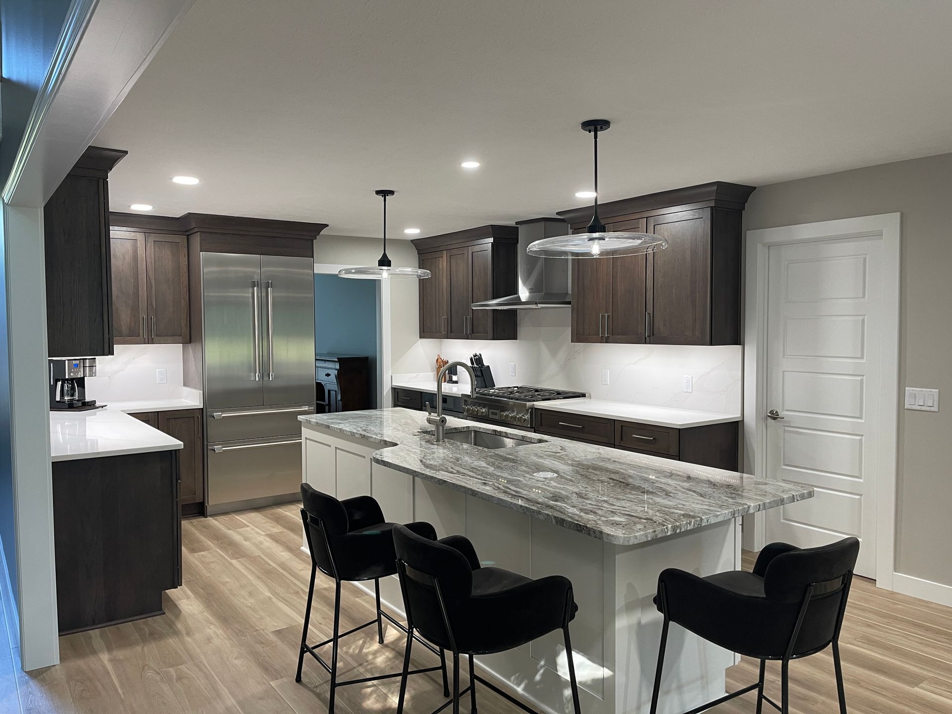 Modern kitchen with dark wood cabinets, stainless steel appliances, and island with granite countertop.