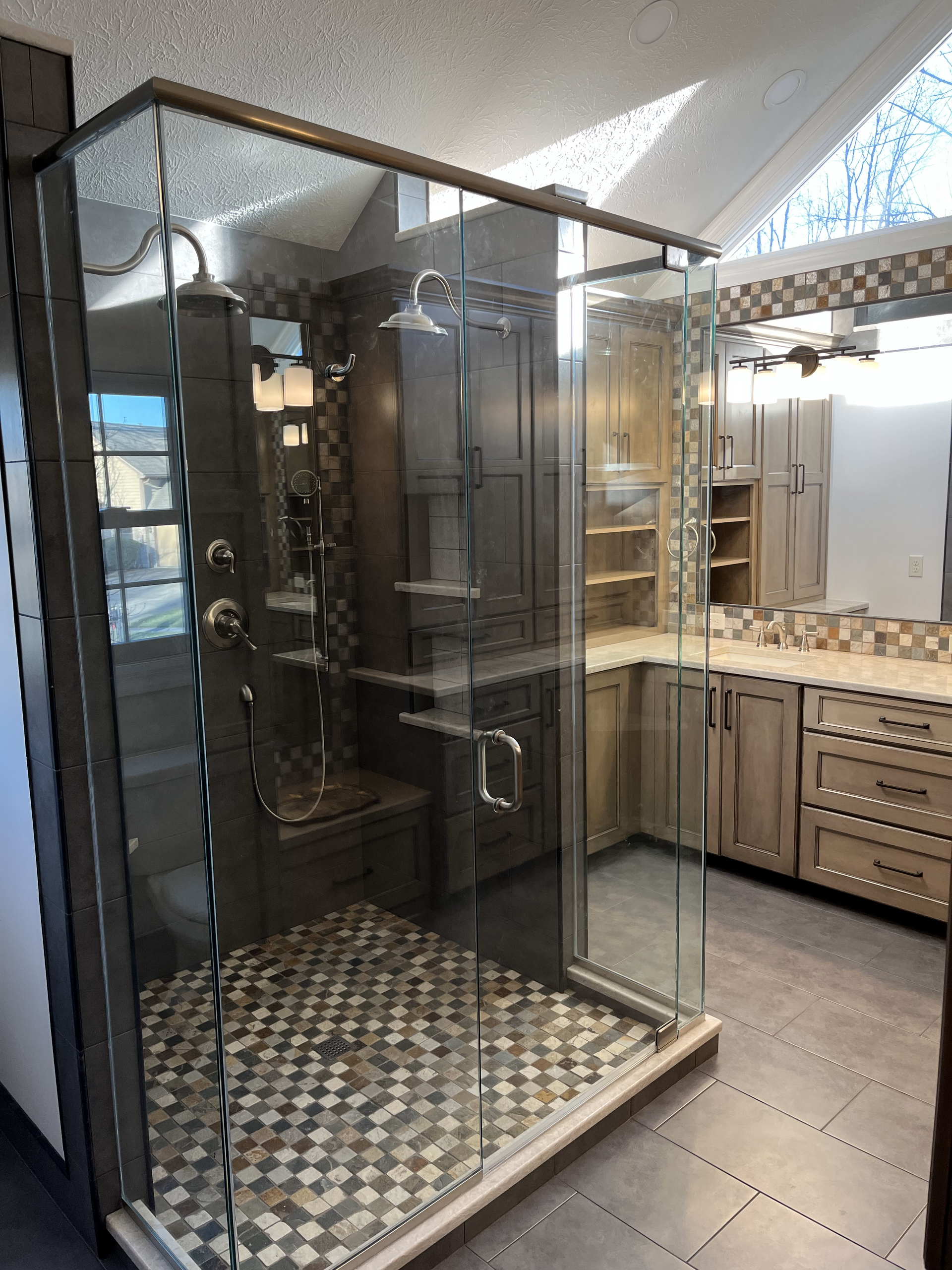 A bathroom with a walk in shower and a vanity.