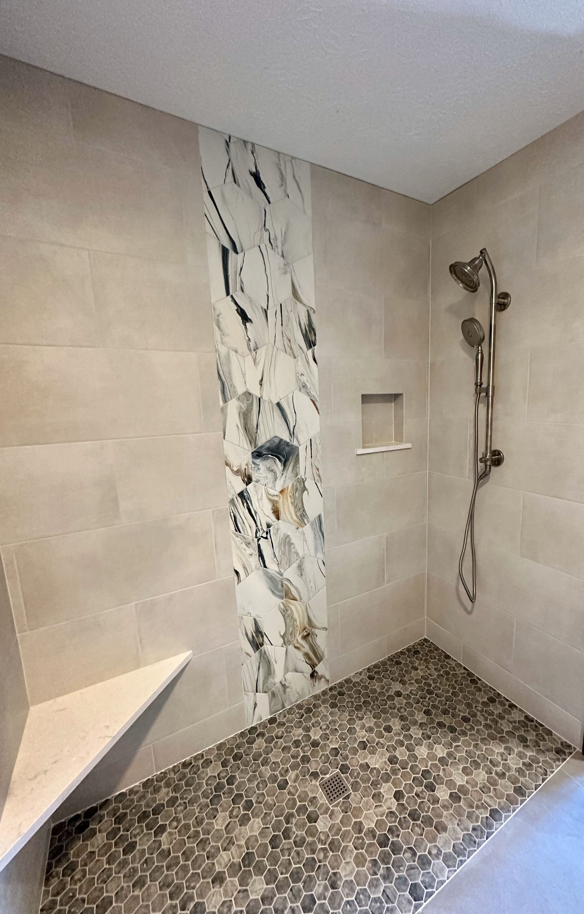 A bathroom with a walk in shower and a marble wall.