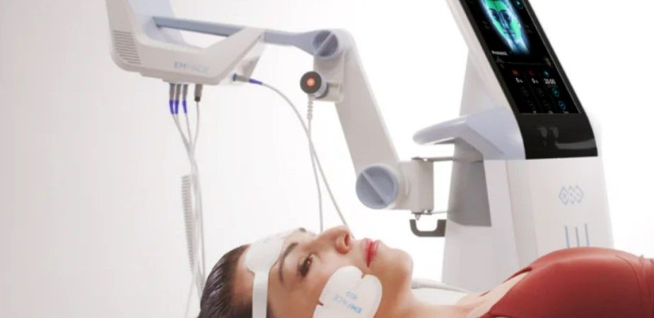Woman undergoing a medical procedure, lying down with head in a robotic arm device; white setting.