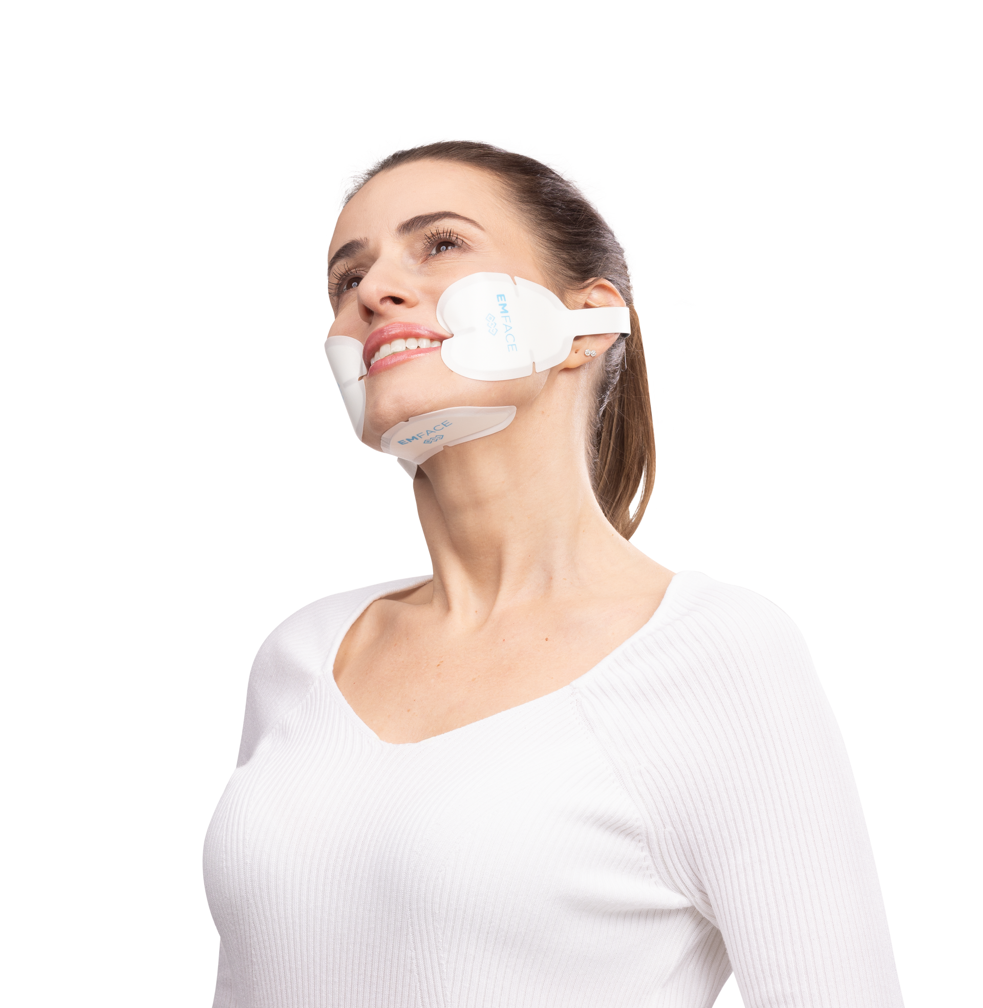 Woman wearing a facial support device, looking up, smiling, in a white sweater, against a white background.