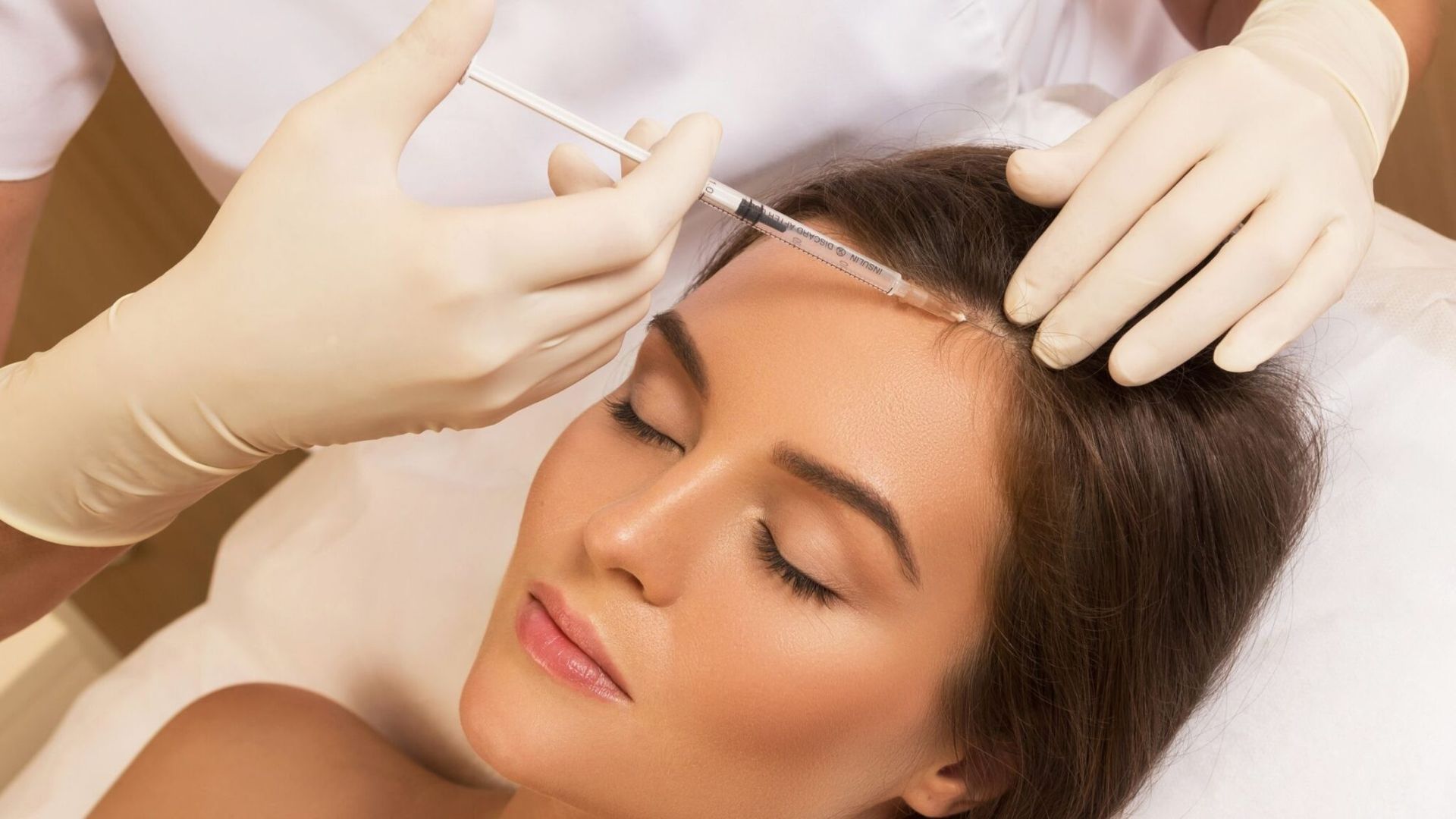 Person receiving injections in scalp; medical procedure in a clinic.