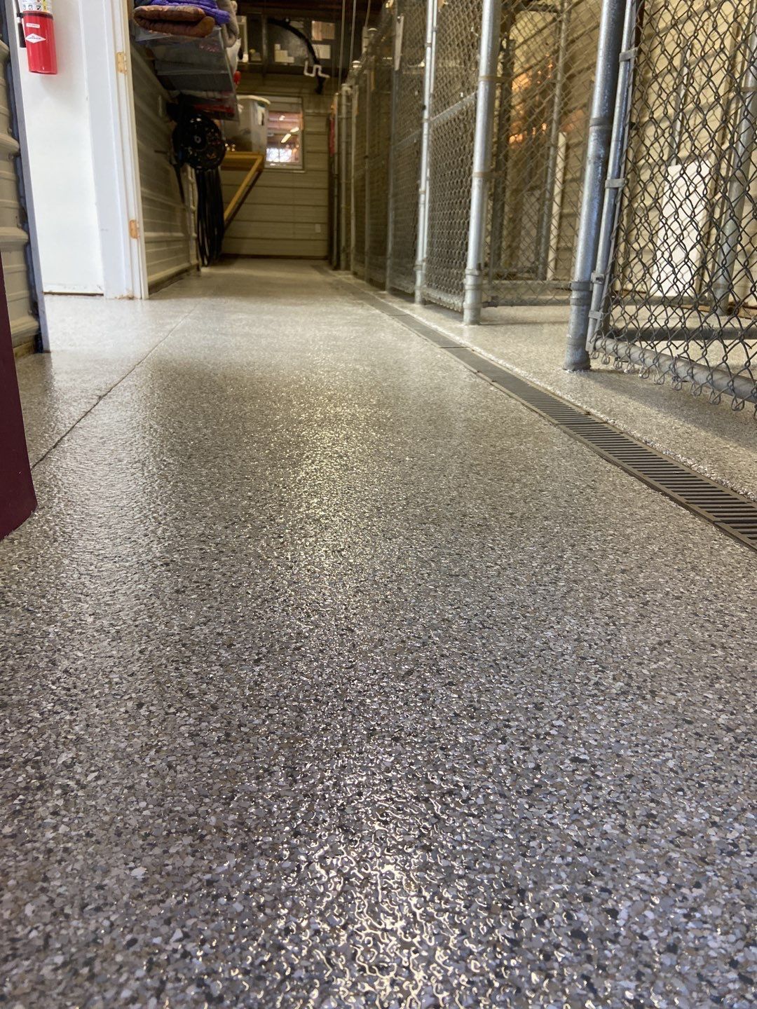 A man is standing in a hallway next to a chain link fence