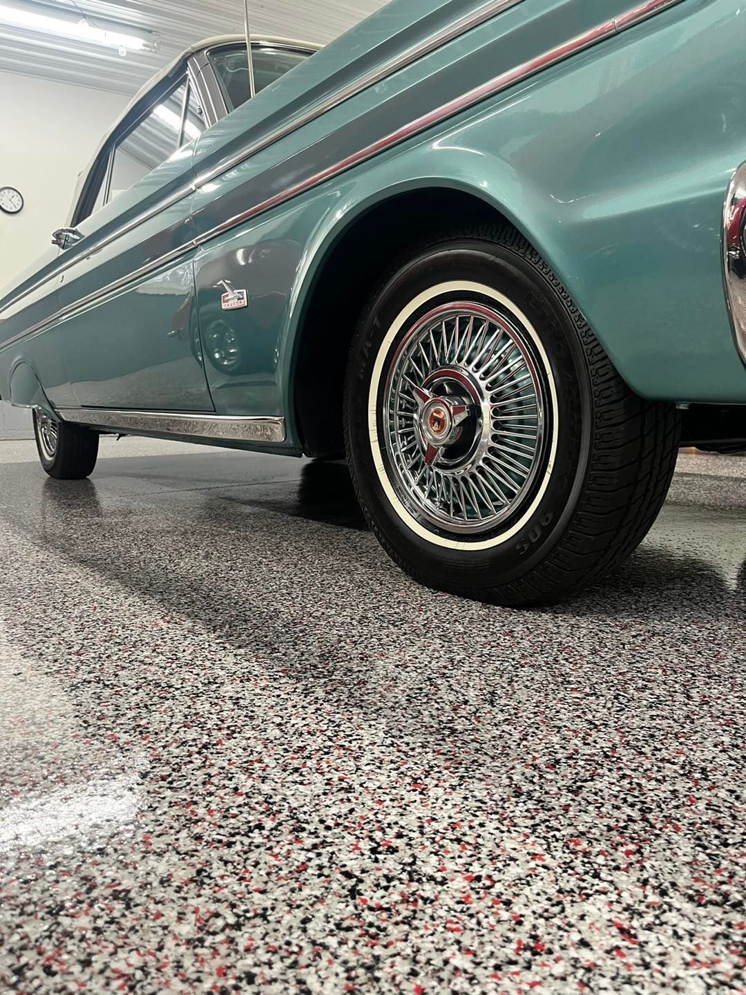 A blue car is parked in a garage with a concrete floor