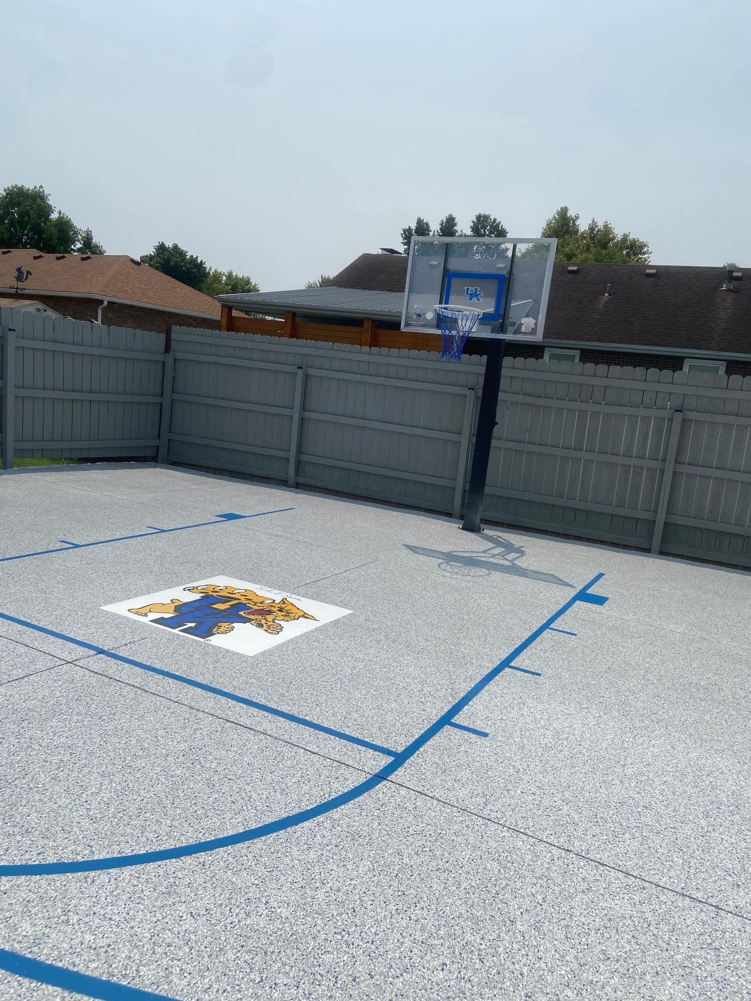 A basketball court with a basketball hoop in the backyard of a house