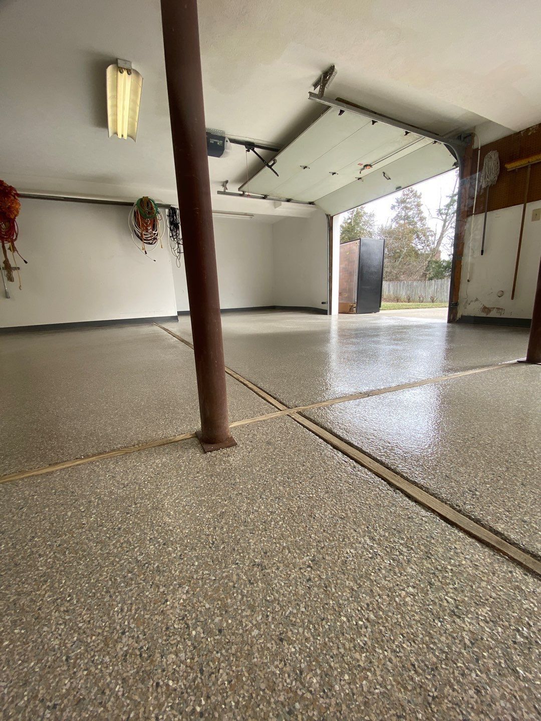 A garage with a concrete floor and a garage door open