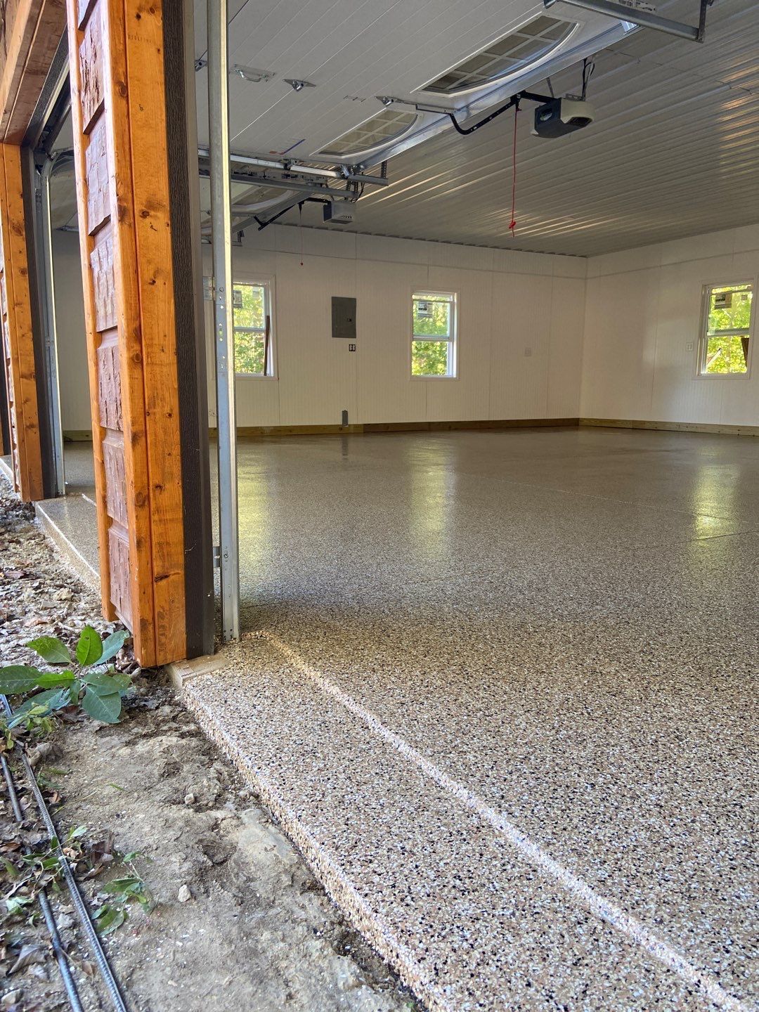 A garage with a concrete floor and a garage door open