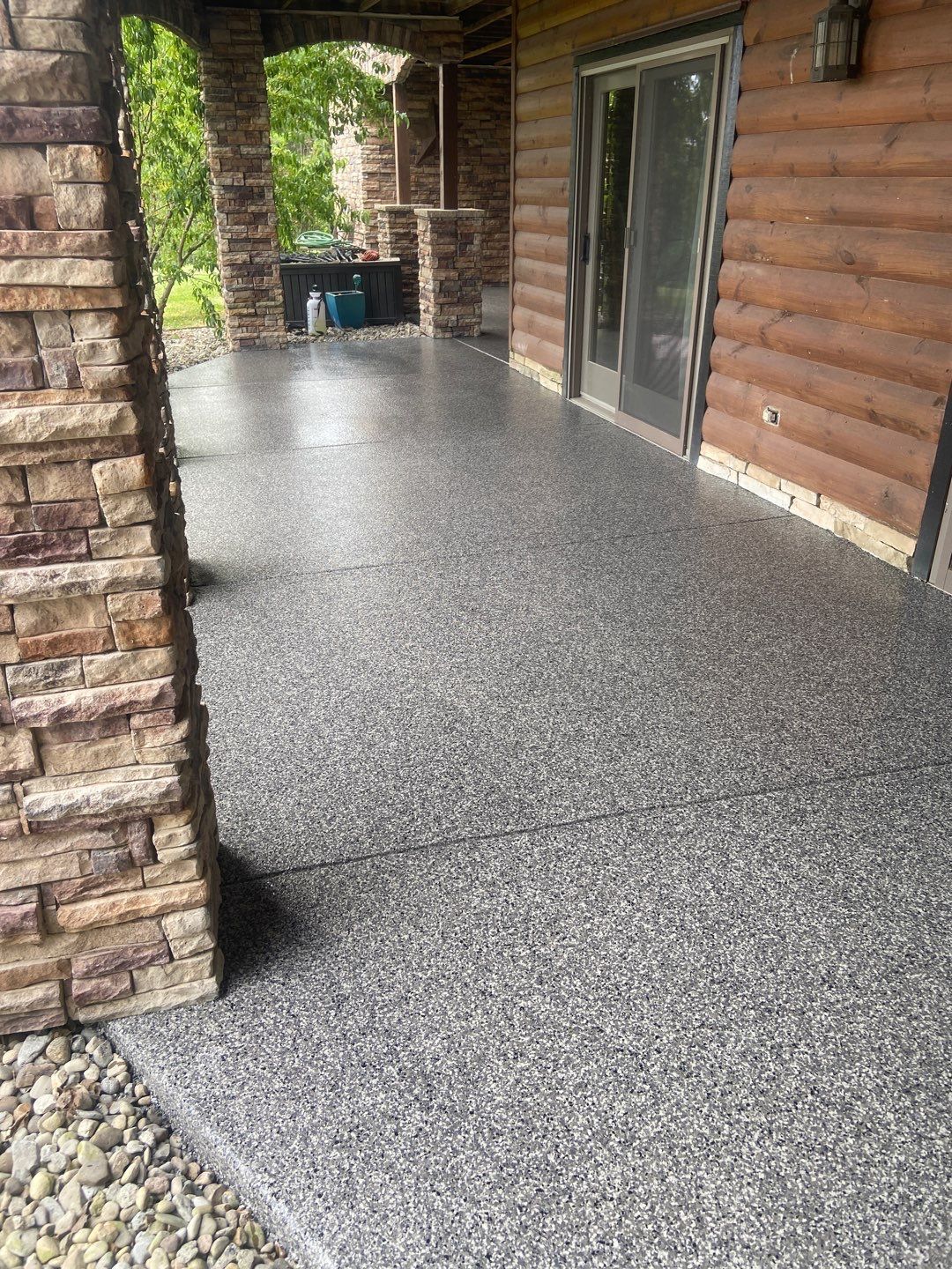 A porch with a concrete floor next to a log cabin