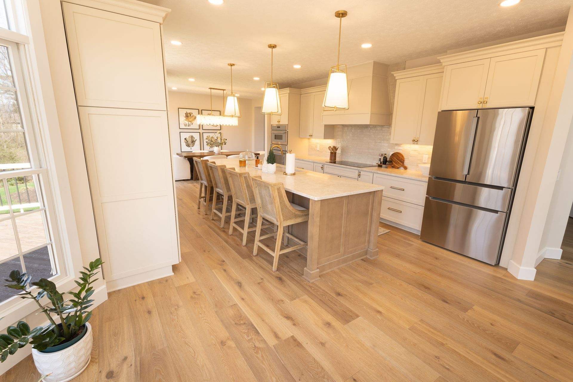Bright modern kitchen with white cabinets, island seating, stainless steel appliances, and hardwood floors