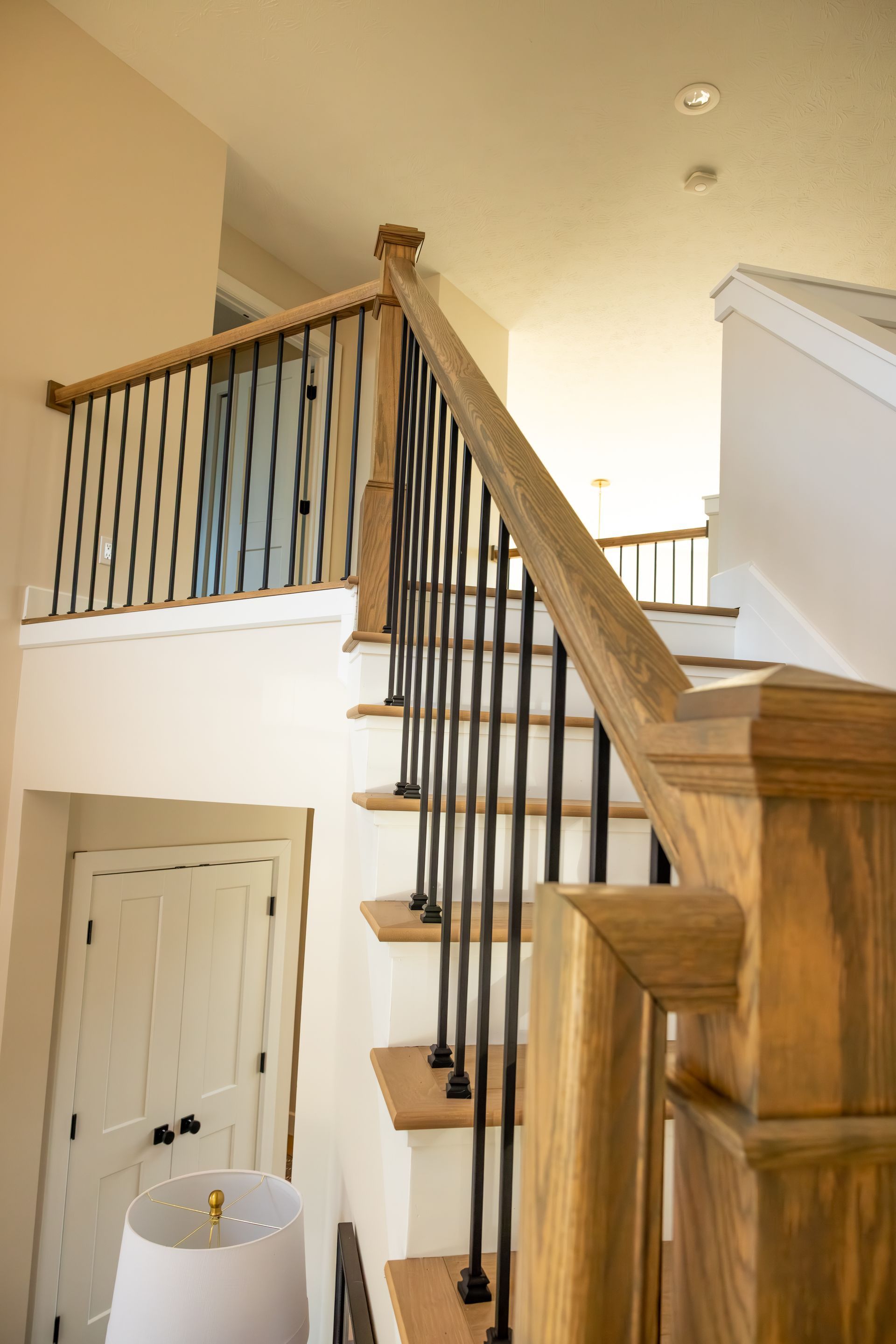 Interior staircase with wooden railings and black balusters in a bright home foyer