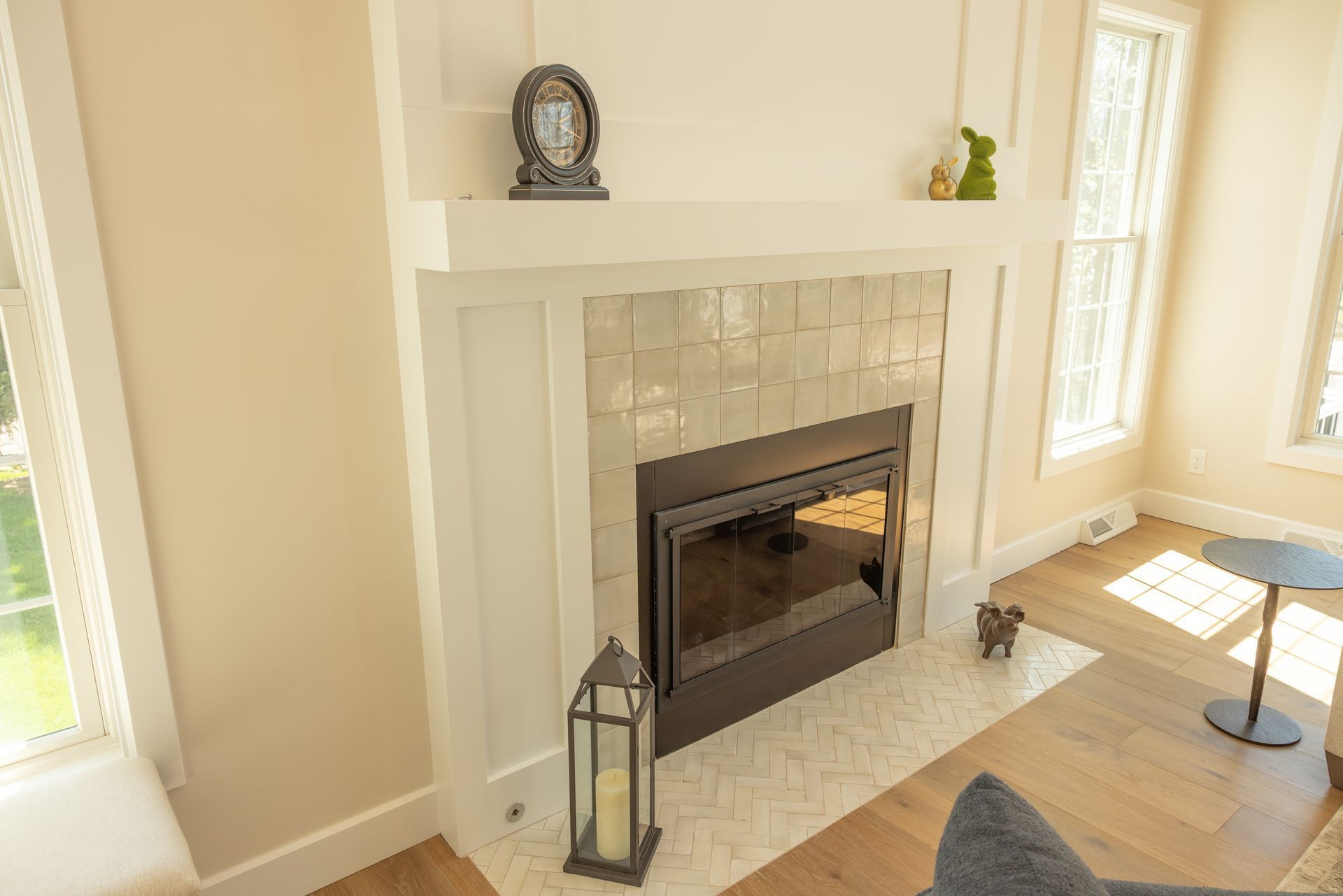 Bright living room fireplace with white mantel, beige walls, and sunlight on the floor
