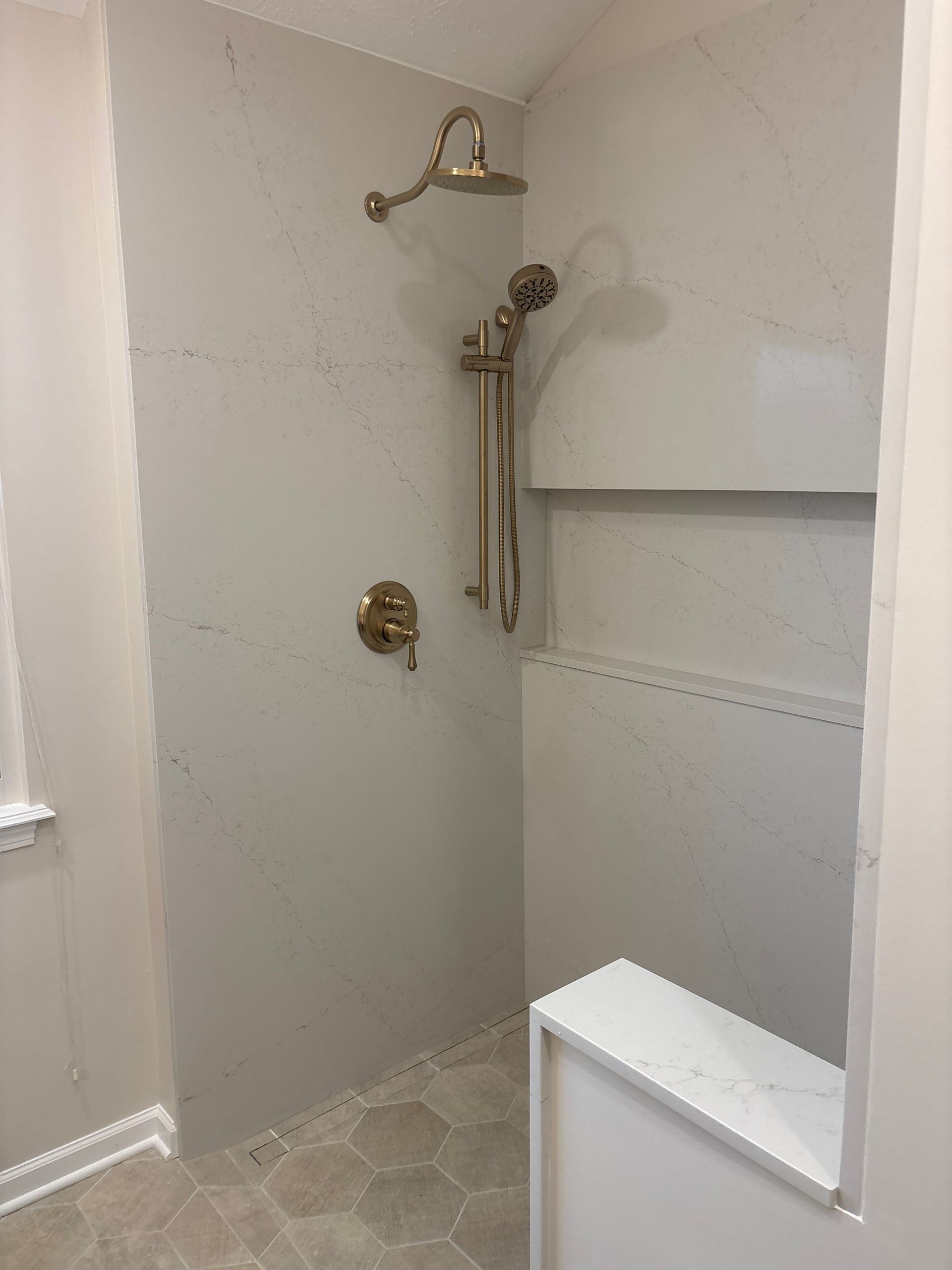 Empty tiled shower stall with a handheld showerhead and built-in shelves.