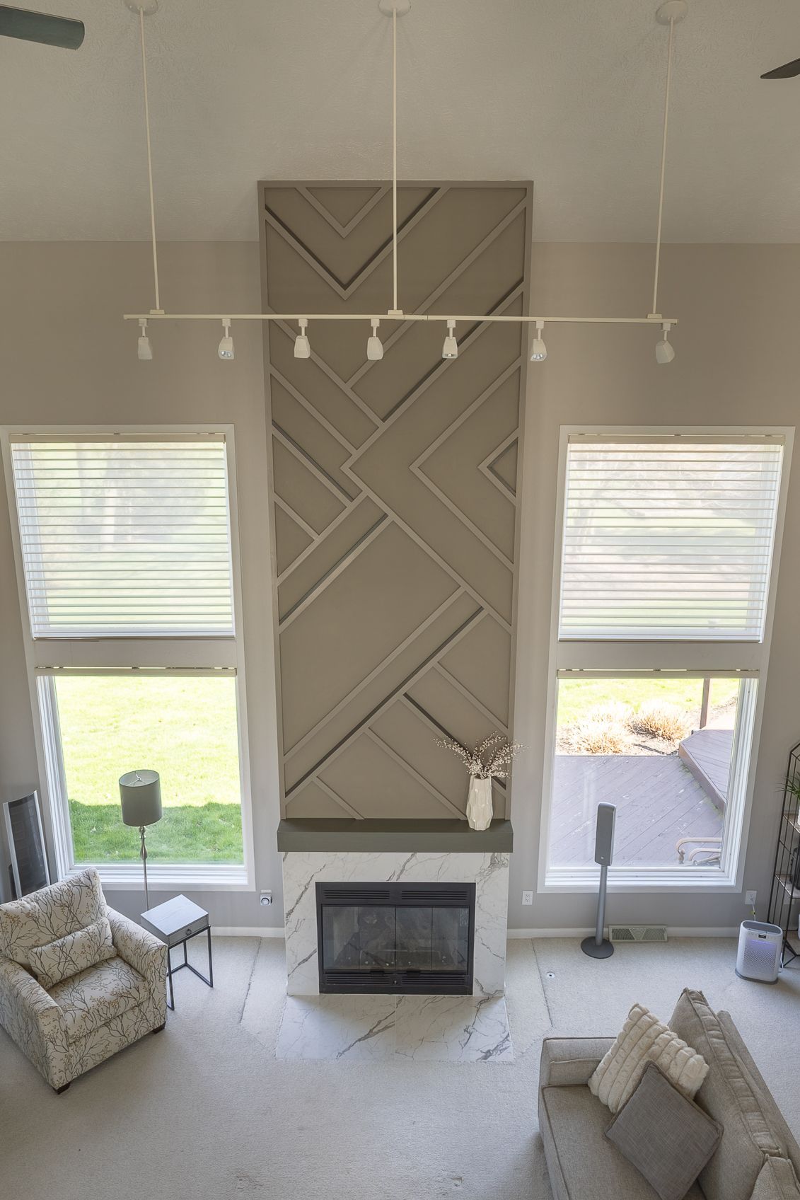 Living room with tall windows, a fireplace, and a large geometric wall panel above it