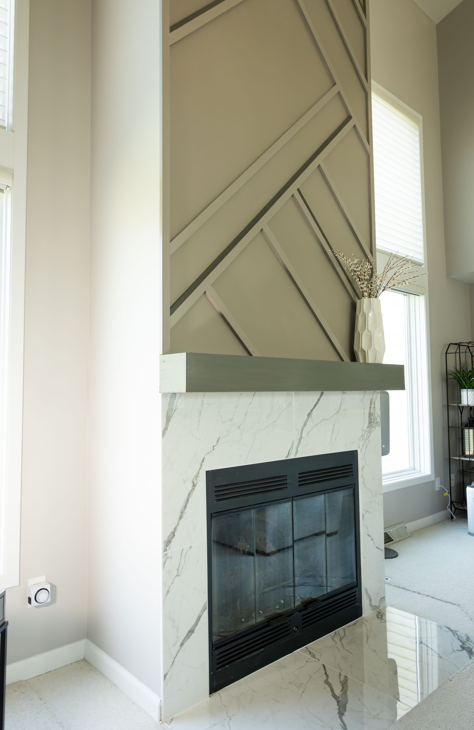 Modern beige fireplace with geometric paneling and marble trim in a bright living room