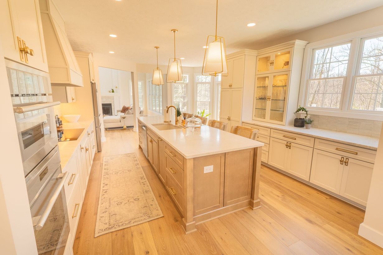 Bright modern kitchen with a large island, white cabinetry, and warm wood floors and accents