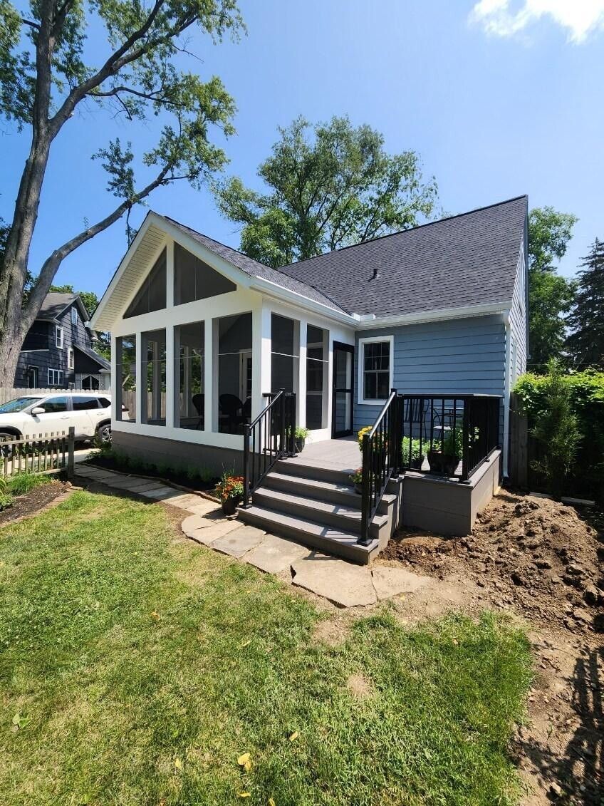 Blue house with a screened porch, grey steps, and a grassy yard.