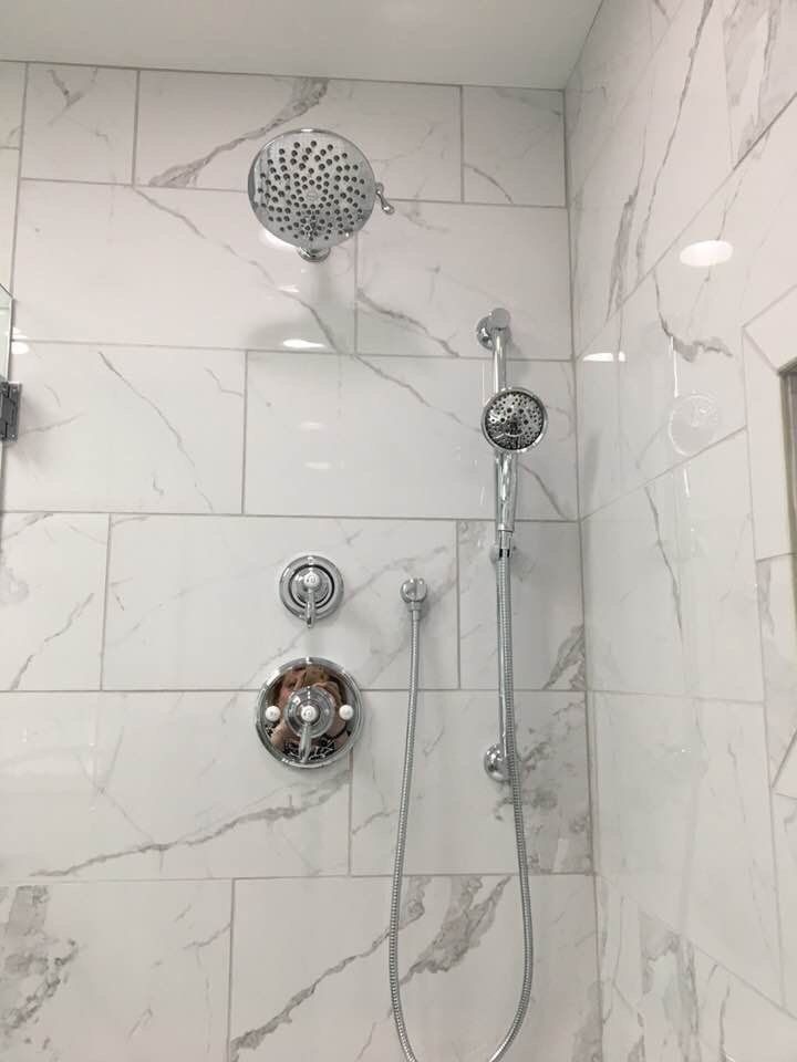 Chrome shower fixtures on white marble tile.