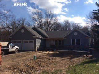 Gray house with a two-car garage. Stone siding and a new roof. Truck parked in front.