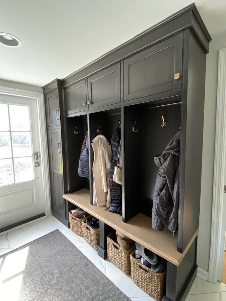 Dark gray mudroom with three open sections for hanging coats, baskets below, and a bench.