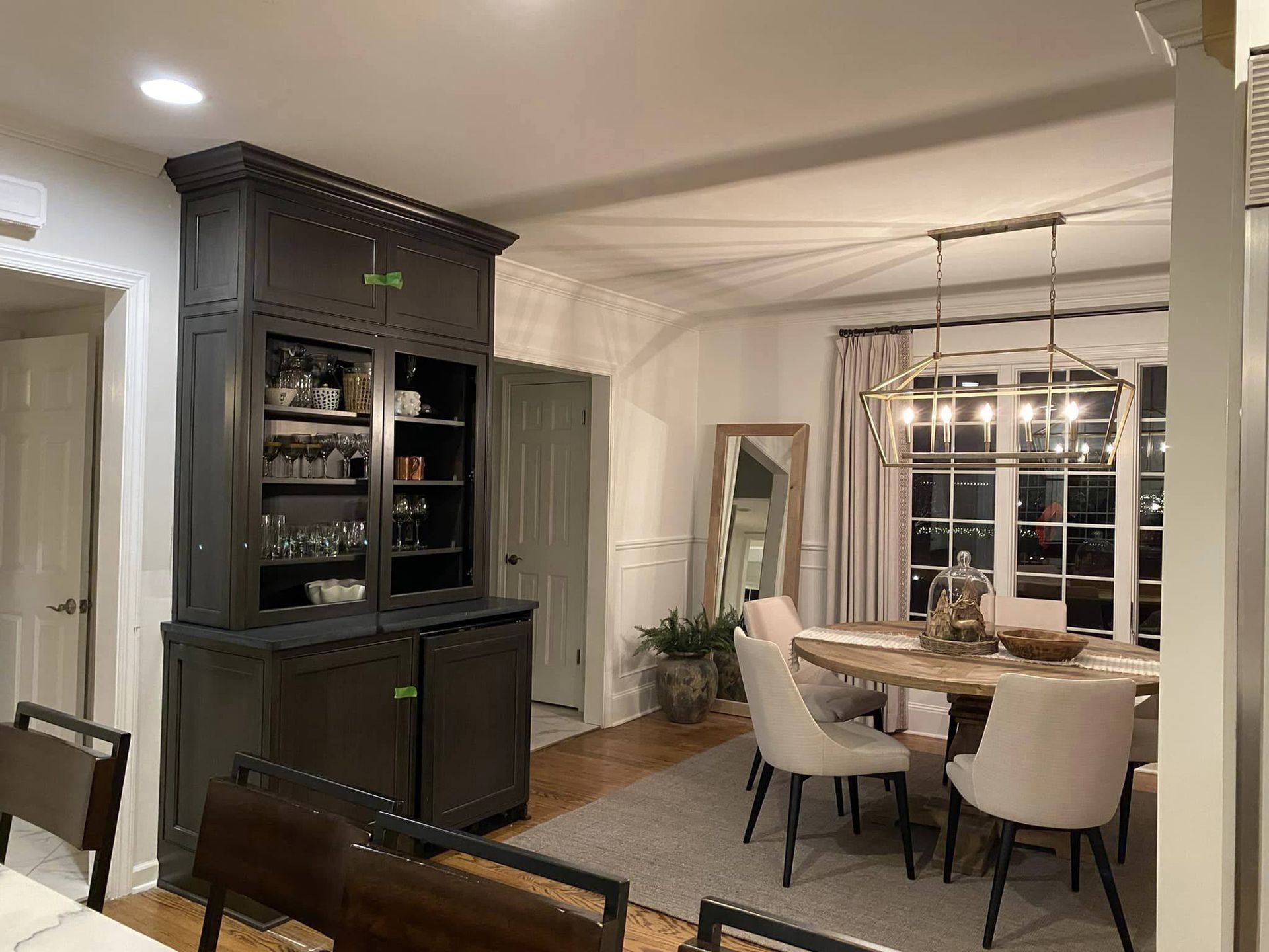 Dark gray hutch in a dining room with a round table and chandelier.