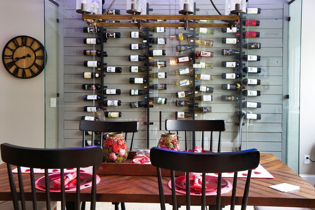 Dining room with wood table, black chairs, wall-mounted wine rack, and decorative clock.