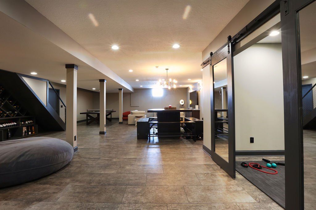 Spacious basement with gray concrete flooring. Dark sliding doors, fitness mat with weights.