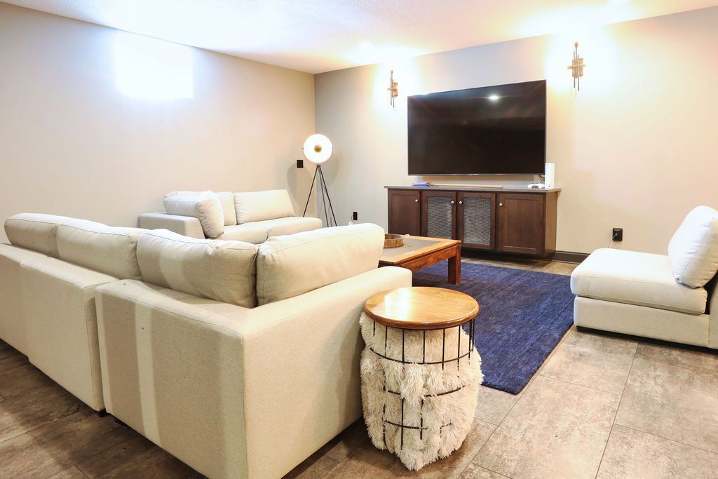 Living room with a large cream-colored sectional sofa, a television, and a blue rug.