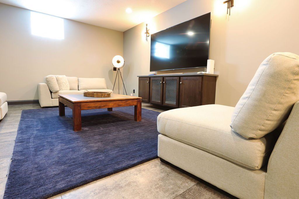 Living room with blue rug, beige sofas, dark wood coffee table, and TV on a dark wood cabinet.