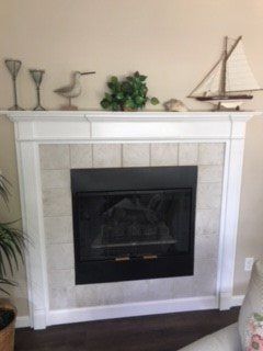 Fireplace with white mantel, cream tile surround, and nautical decor.
