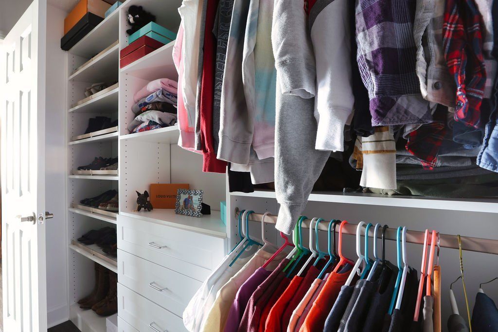 Closet with organized shelves, hanging clothes, and colorful hangers.