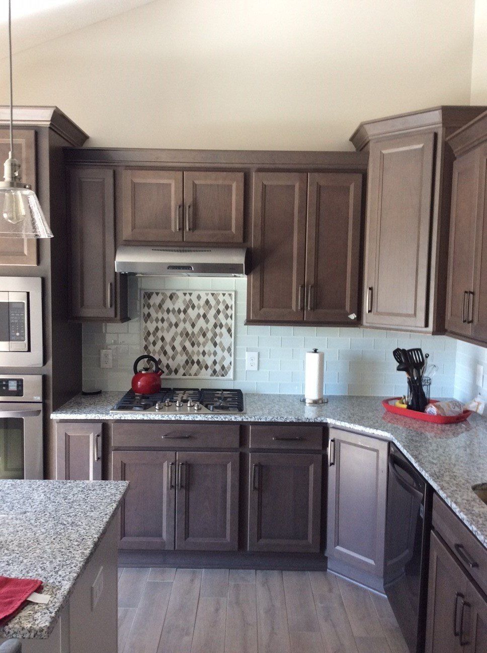 Brown kitchen cabinets and countertops with a stove and backsplash.