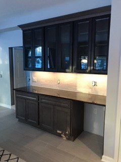 Dark gray kitchen cabinets with a black countertop. Light tile backsplash.