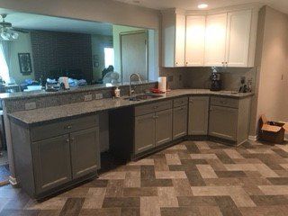 Gray and white kitchen with granite countertops, accessible sink area, and herringbone floor.