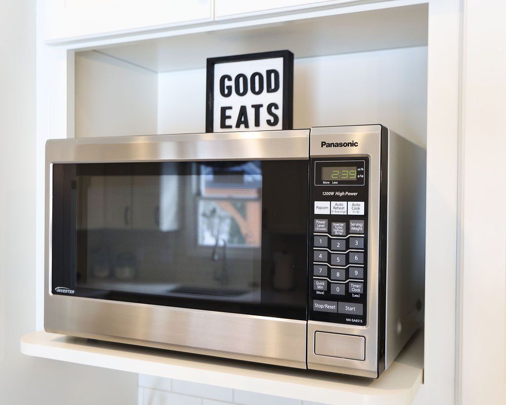 Microwave in a white cubby, with 