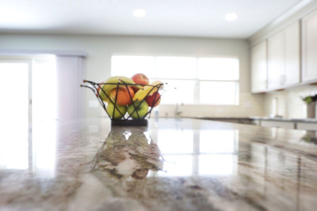 Fruit basket on a granite countertop in a bright kitchen.