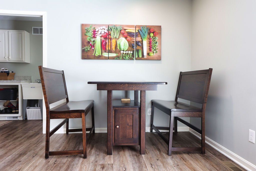 Dining table and two chairs with artwork on the wall in a kitchen.